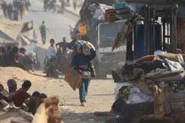 A displaced Palestinian woman, fleeing northern Gaza due to an Israeli military operation, walks with he belongings as she moves southward after Israeli forces ordered residents of Gaza City