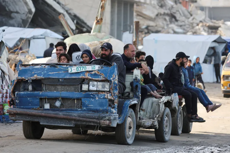 A displaced Palestinian drives his vehicle damaged by Israel's genocidal war as he transports residents in Gaza City