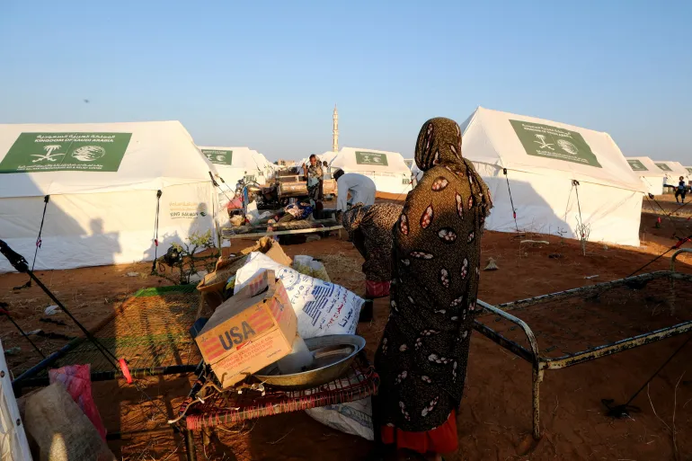 A displaced woman stands in front of an empty cardboard box labeled "USA", at displaced persons camp, in El Obeid, North Kordofan State, Sudan, January 12, 2026. REUTERS/El Tayeb Siddig