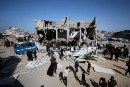 Palestinians stand outside destroyed building