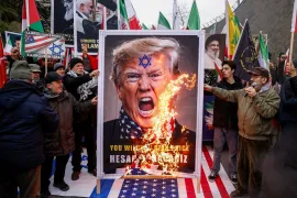 Demonstrators burn a poster of US President Donald Trump.