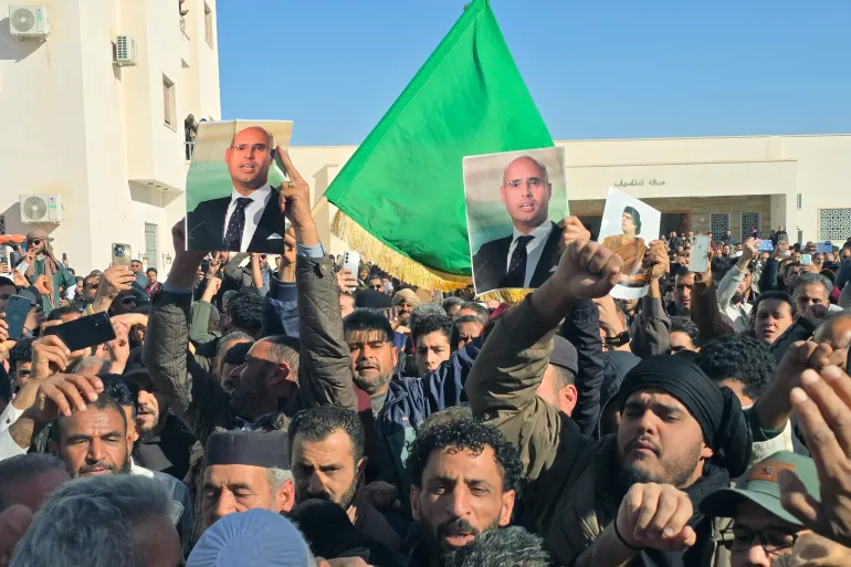 Libyans hold up images of the late Saif al-Islam Gaddafi, the son of Libya's late longtime ruler, prior to his funeral in Bani Walid