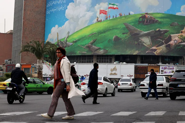 An Iranian woman walks past a huge anti-US billboard