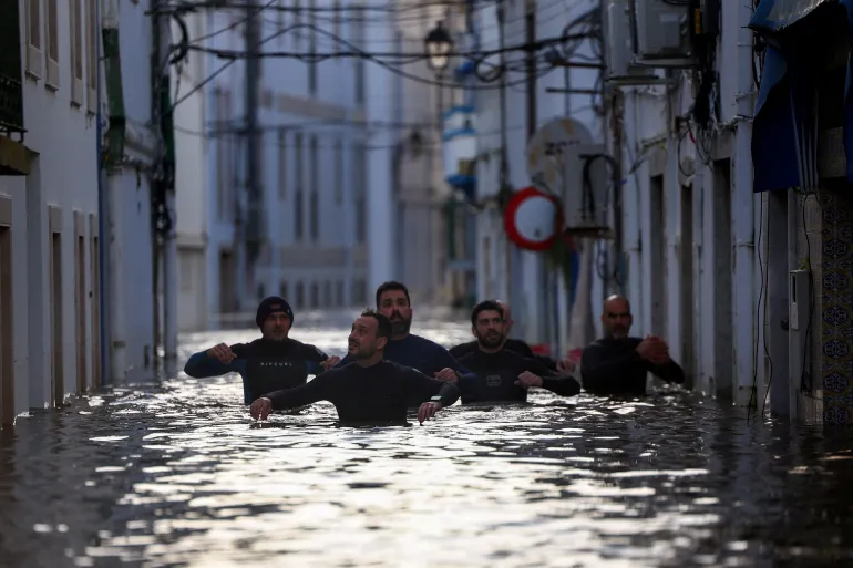 Volunteers wade through a flooded street after Storm Leonardo passed by Alcacer do Sal, Portugal, February 5, 2026. REUTERS/Pedro Nunes TPX IMAGES OF THE DAY